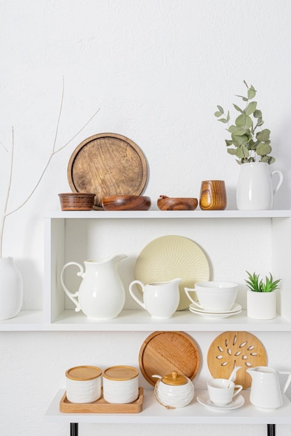 Beautiful front vertical view of the white wooden open shelves with dishes made of ecofriendly materials The concept of a clean house without waste