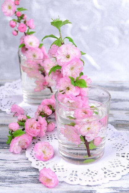 Beautiful fruit blossom in glass on table on grey background