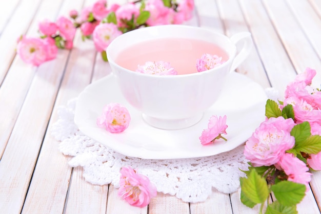 Beautiful fruit blossom with cup of tea on table closeup