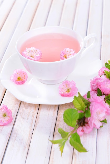 Beautiful fruit blossom with cup of tea on table closeup