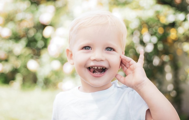 Beautiful fun day for cute little boy in nature happy boy standing in grass at sunny summer day