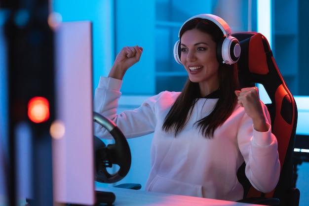 The beautiful gamer girl with headphones playing video games