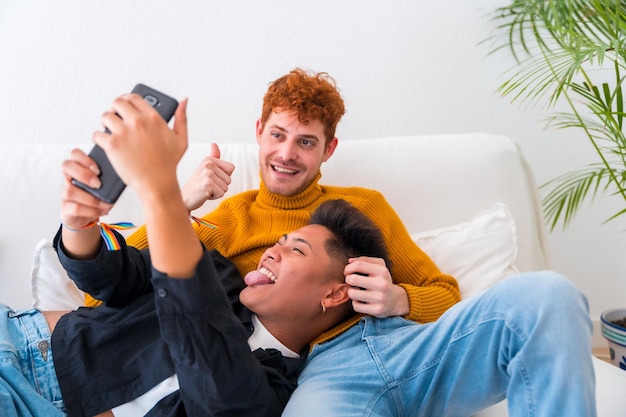 Bella coppia gay che è romantica al chiuso sul divano coppia gay che si fa un selfie