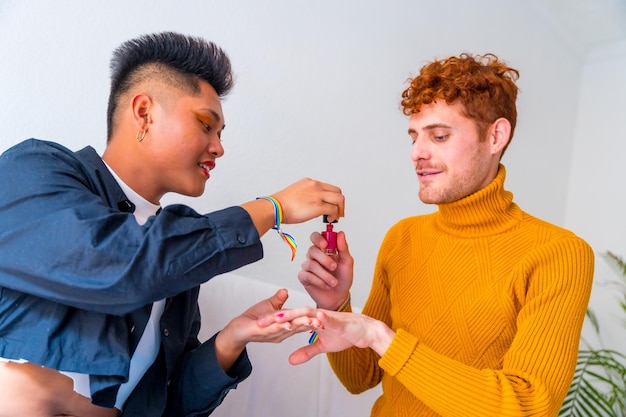 Beautiful gay couple doing makeup painting their nails and having fun indoors at home lgbt concept