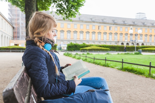 Красивая немецкая женщина читает книгу в парке