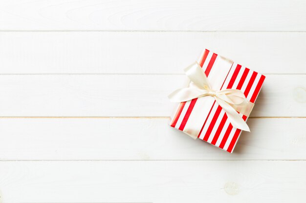 Beautiful gift box with a coled bow on the white wooden table. 