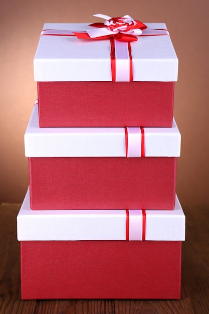 Фото Красивые подарочные коробки на столе на коричневом фоне