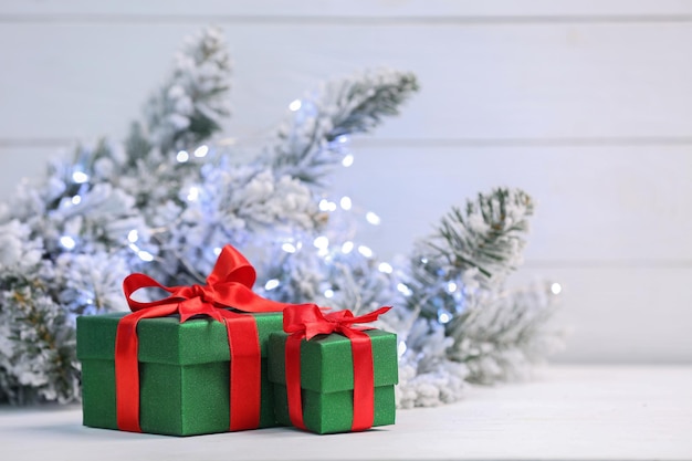 Beautiful gift boxes on white table against blurred festive lights space for text Christmas present