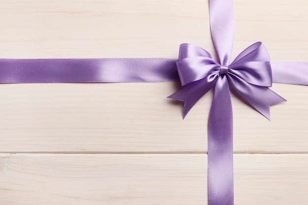 Photo beautiful gift lilac bow and ribbon on white wooden background. congratulations concept.