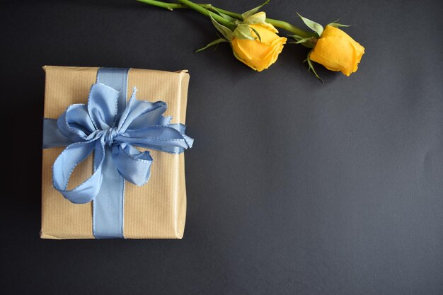 A beautiful gift and two yellow roses on a black background