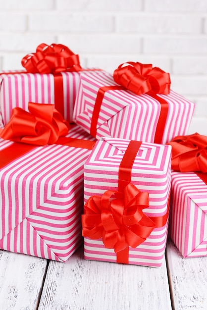 Beautiful gifts on table on brick wall background