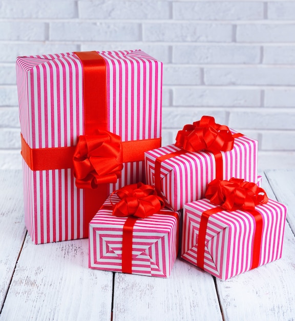 Beautiful gifts on table on brick wall background