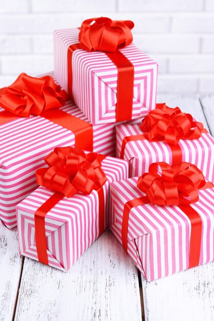 Beautiful gifts on table on brick wall background