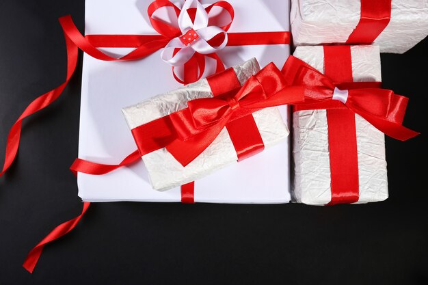 Beautiful gifts with red ribbons, on dark surface