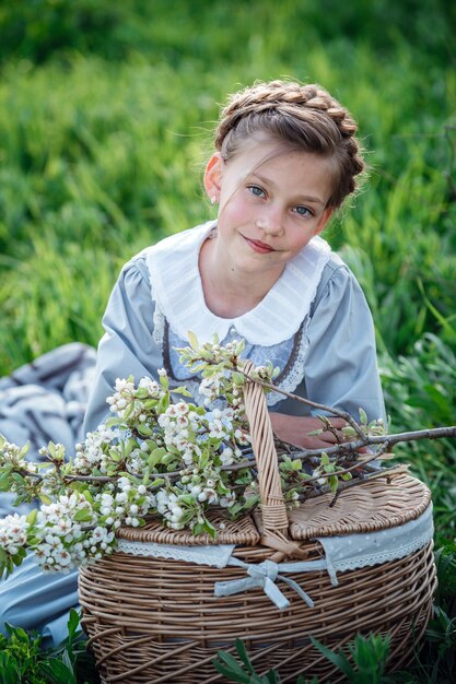 Beautiful girl 6-7 year old posing in garden. Easter time. enjoys spring and warmth. Beautiful spring garden. Happy childhood, peace and happiness concept. Aromatic blossom and retro vintage.