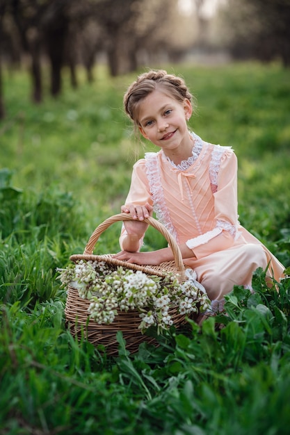 Красивая девочка 6-7 лет позирует в саду. Время пасхи. любит весну и тепло. Красивый весенний сад. Счастливое детство, мир и концепция счастья. Ароматные цветы и ретро-винтаж.