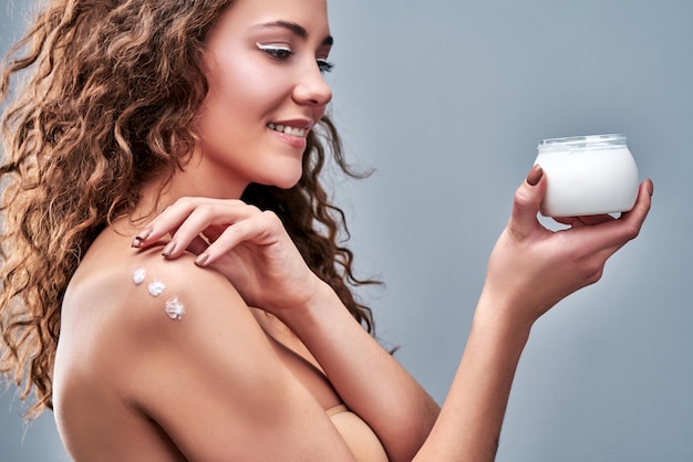 Photo beautiful girl applying moisturizing cream isolated on grey background