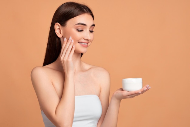 Beautiful girl applying skin care cream on her face