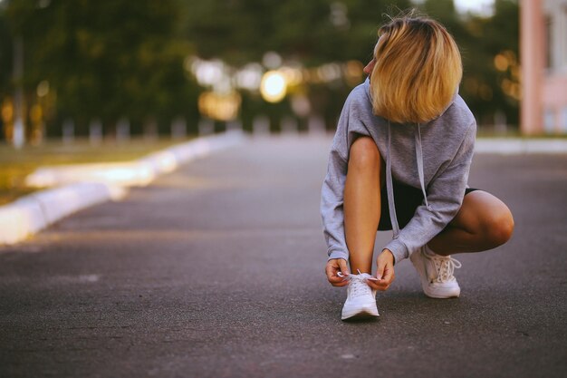 beautiful girl athlete sitting tying shoelaces on white sneakers vintage photo processing