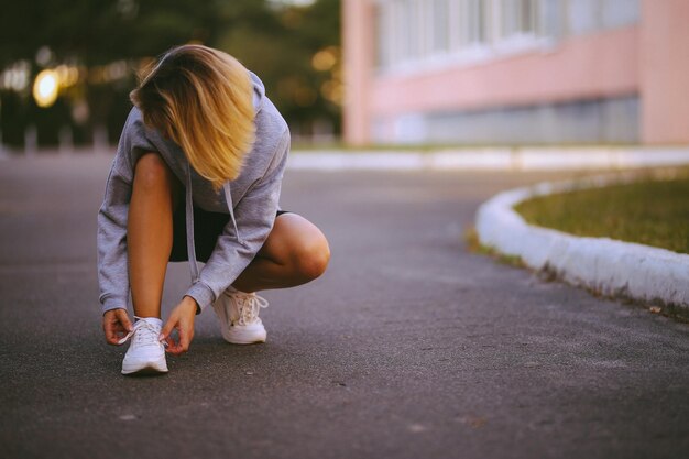 beautiful girl athlete sitting tying shoelaces on white sneakers vintage photo processing