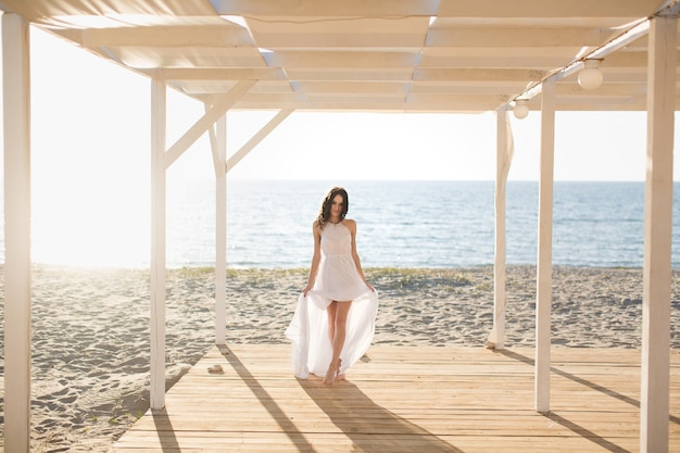 Beautiful girl on the beach in a white dress.