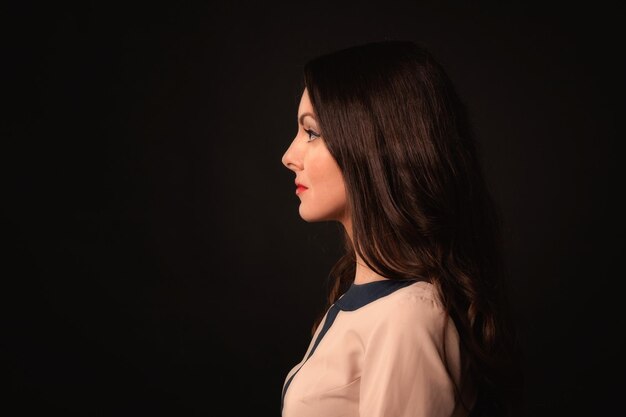 Beautiful girl in a beige dress on a dark background