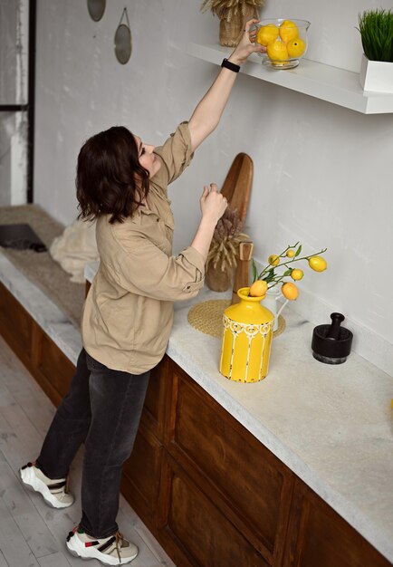 Foto bella ragazza in una cucina beige con limoni gialli in stile siciliano italia