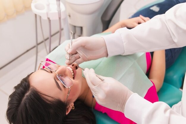 Photo beautiful girl being receiving dental treatment from her dentist in the dental office