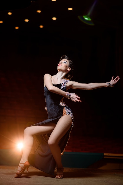 Beautiful girl in black dress dancing on stage.