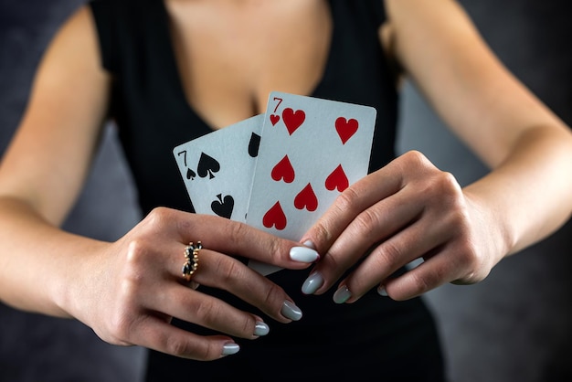 Beautiful girl in black dress holds ace of poker cards near sexy cleavage