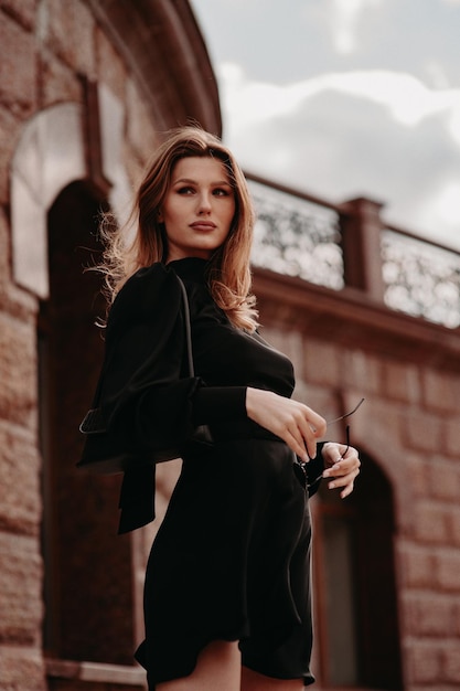 Beautiful girl in a black dress on the street