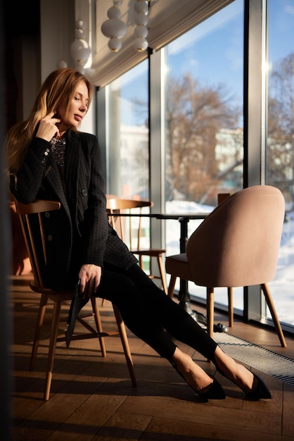 Beautiful girl in a black jacket in a cafe posing on the camera