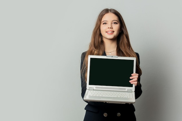 Bella ragazza in giacca nera con computer portatile su sfondo bianco