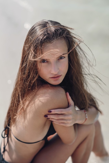 Beautiful girl in a black swimsuit on summer beach.