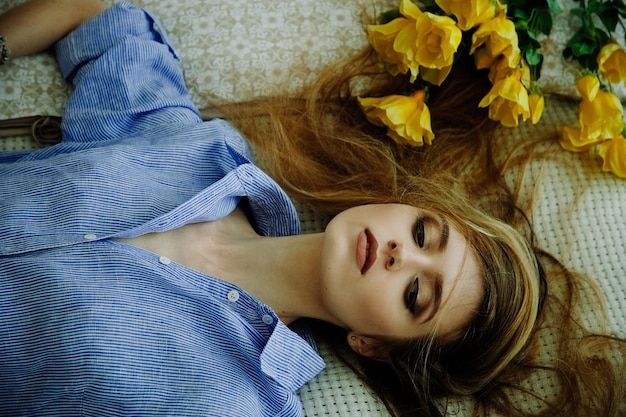 beautiful girl blonde with yellow flowers looking into the distance top view fashion shooting