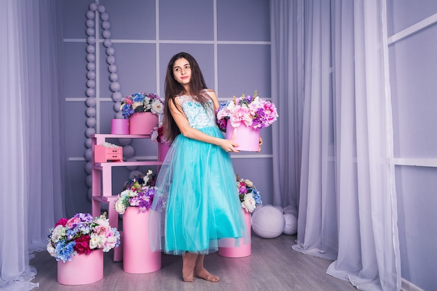 Beautiful girl in blue dress with decor of flowers in baskets