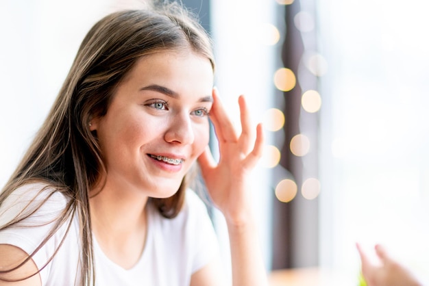 Beautiful girl in braces with hand near face