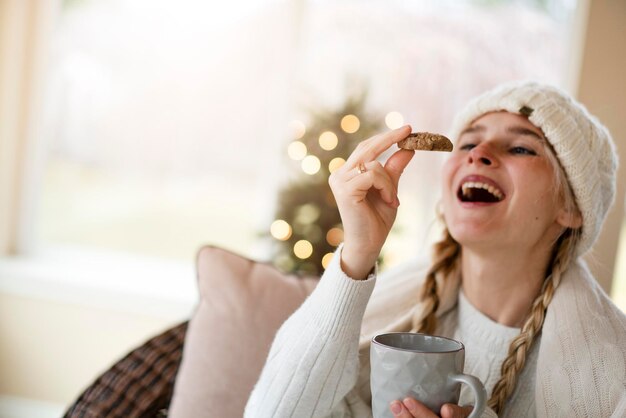 A beautiful girl in a bright Christmas room reads a book and drinks tea