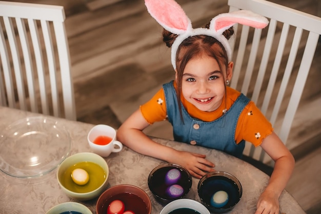 beautiful girl in bunny ears paint Easter eggs