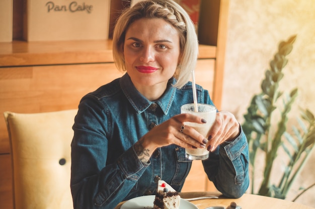 Photo beautiful girl in a cafe enjoying a cold cocktail. hipster girl holding summer cocktail. refreshment drink in sunny day