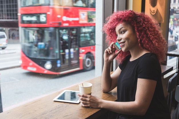 Bella ragazza in un caffè parlando su smart phone