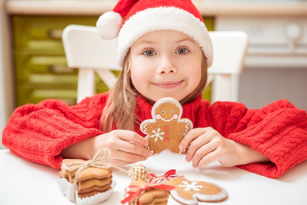 Photo beautiful girl child plays with ginger cookies