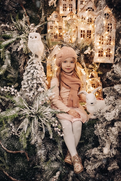 Bella ragazza in una decorazione natalizia con molti alberi sotto la neve e luci sullo sfondo