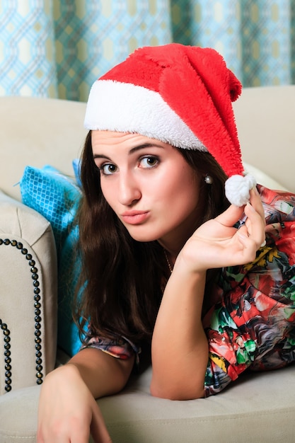 Beautiful girl in a Christmas hat lying on the sofa