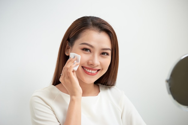 Beautiful girl cleans the face of makeup with a cotton pad