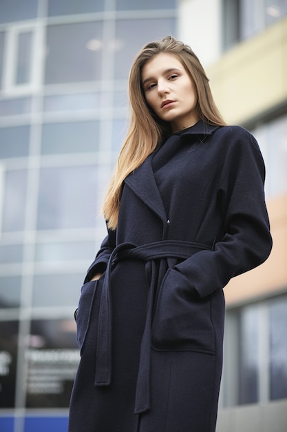 Beautiful girl in a coat in business downtown of the cloudy