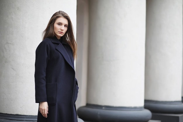 Beautiful girl in a coat in business downtown of the cloudy