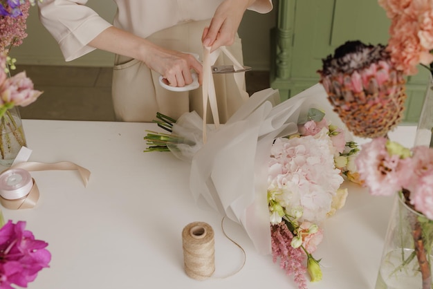 Beautiful girl collects a bouquet of flowers in a flower shop