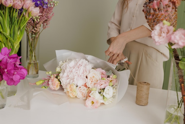 Beautiful girl collects a bouquet of flowers in a flower shop