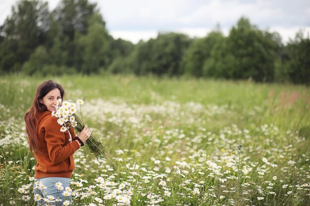 Photo beautiful girl collects daisies in summer day in afield